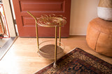 Vintage Hollywood Regency bar cart's brass frame, round bottom shelf, and rolling wheels.