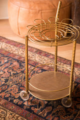 Brass lower shelf and clear caster wheel of the 1960s vintage bar cart.