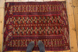 Feet on Vintage Turkmen rug's central geometric guls in madder red, ivory, navy.