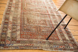 Intricate serpent design border with geometric motifs and distressed fringe on a Caucasian rug corner.