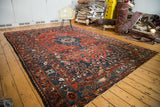 Distressed vintage Bakhtiari carpet with rectilinear patterns in brick red, indigo blue, and ivory.