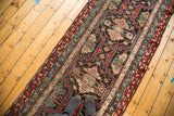 Repeating tribal geometric medallions in madder red and teal on a vintage Caucasian runner.