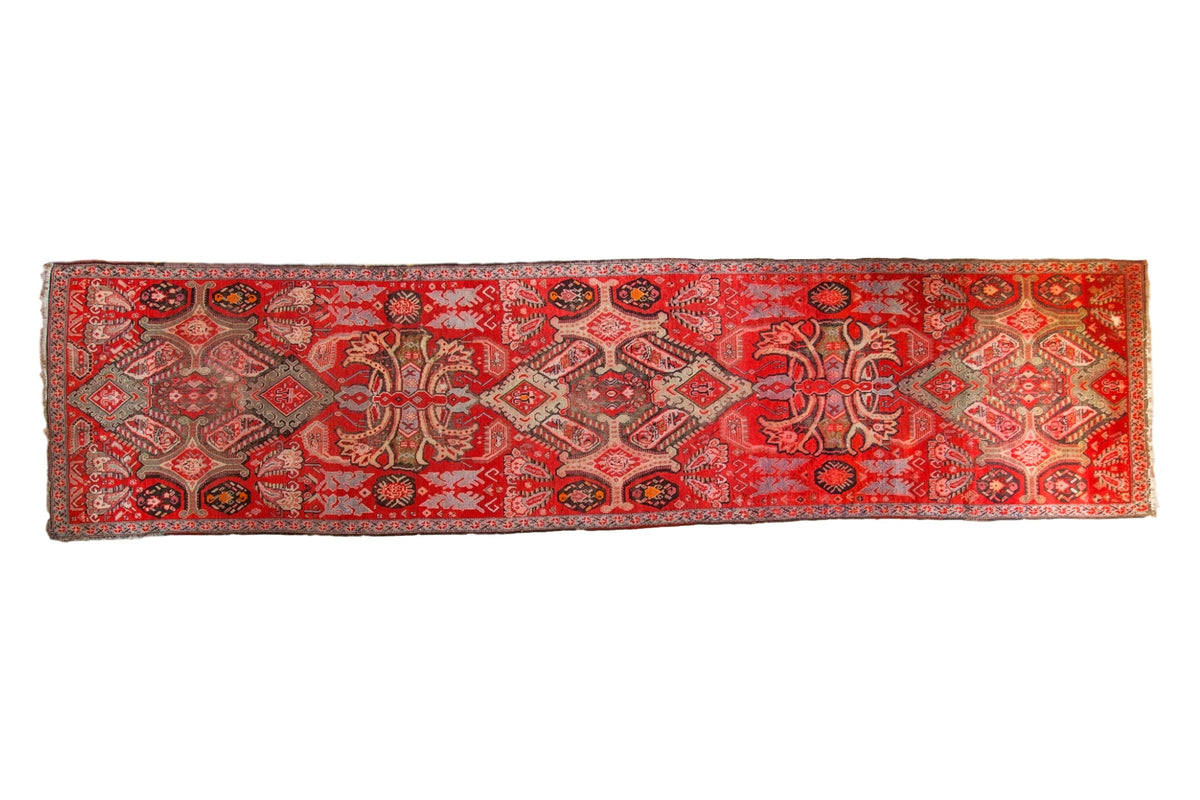 Distressed Antique Karabagh runner: brilliant blood orange field, repeating medallions, floral motifs.