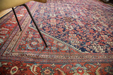 Angled view of vintage distressed Persian Mahal carpet, indigo guli-hinnai field and black cherry border.