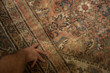 Close-up of distressed antique Mahal rug showing faded Herati pattern and small split.