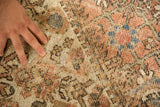 Hand pointing to a visible hole revealing the foundation of the distressed Mahal carpet.