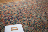 Finely woven, distressed pile texture with intricate rust, navy, and ivory patterns.