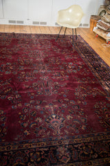 Distressed plum purple field of the Turkish carpet with bursting floral planters and navy border.