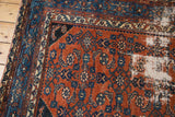 Hard distressed areas of a vintage Malayer rug, showcasing madder root red and sky blue motifs.