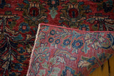 Hand-knotted Sarouk rug foundation details, showing exquisite blue floral motifs on a cherry red field.
