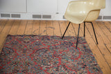 Cherry red field of a vintage Sarouk runner with exquisite floral bouquets and secured end.