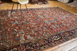Vibrant cherry red and jewel tone blue patterns on a distressed vintage Heriz carpet.