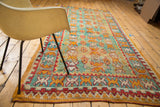 Reciprocating geometric motifs in mint green, orange, and red on the Vintage Murat rug's textured pile.
