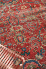 Antique Sultanabad's coral-red main field, exhibiting worn texture and intricate floral motifs.