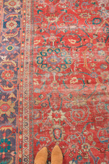 Storied coral-red field and unique lavender-purple border of an antique Sultanabad rug, worn to knot heads.