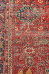 Antique Sultanabad rug's worn coral-red field, unique lavender-purple border, and intricate floral pattern detail.