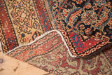Antique Fereghan carpet folded corner reveals muted border and visible hand-knotted foundation.