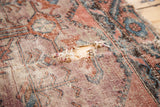 Distressed antique Lilihan rug detail with a visible split, worn pile, and faded terracotta, mauve, and charcoal patterns.