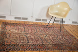 Antique Distressed Lilihan rug with visible hole and unique elongated agricultural motifs.