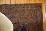 Distressed Vintage Belouch rug with faded diamond gul pattern in madder red, navy, and chocolate brown.