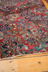 Exquisite floral bouquets on a vintage Sarouk rug's cherry red field and secured fringe.
