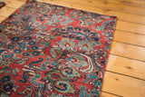 Exquisite floral bouquets and curvilinear motifs on a vintage cherry red Sarouk rug.