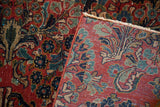 Vintage Sarouk's cherry red field, ornate floral motifs, and hand-knotted foundation.