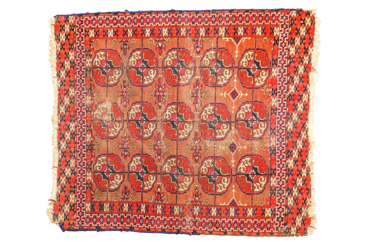 Decoratively distressed vintage Turkmen square rug with repeating red and navy Bokhara gul motifs.