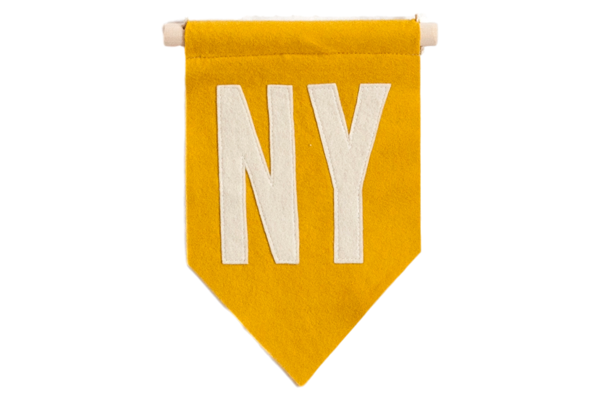 Mustard yellow felt pennant with cream stitched "NY" letters hanging from a wood dowel.
