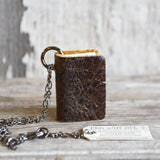 Brown reclaimed leather miniature book necklace with textured cover and gunmetal chain.