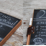 Reclaimed wood edge and dark leather strap securing chalk pencil on the chalkboard pad.