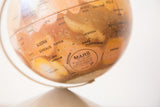 Close-up of the vintage Mars globe, showing 'MARS by replogle' label and rust-toned craters.