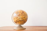 Vintage Mars globe displaying orange-brown surface topography and a golden stand.