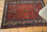 Geometric sapphire blue borders framing ruby red minimalist motifs on a vintage Malayer rug.