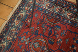 Vintage Malayer rug corner: ruby red field, sapphire blue geometric motifs, and visible white knots.