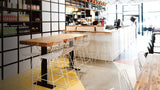 White wire Lucy Counter Stools arranged around a wooden table.