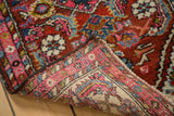 Vintage Persian Hamadan rug corner, revealing its fluorescent blush pink border and hand-knotted underside.