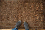 Vintage Belouch runner's repeating gul motifs with germinating flowers, soft texture underfoot.