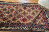 Vintage Belouch rug with serrated guls in red and blue, and geometric zig-zag and wave borders.