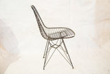 Sculptural profile of a mid-century modern Eames wire chair highlighting the Eiffel base.