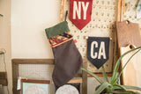 Luxe green holiday stocking with a reclaimed rug fragment cuff displayed as holiday decor.