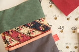 Textured green suede cuff and geometric antique rug fragment in red and navy.
