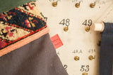 A close-up of the red Old New House tag on the stocking's black linen and rug fragment seam.