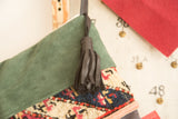 Black leather tassel and green suede cuff detail on a reclaimed rug fragment stocking.