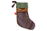 Holiday stocking with a green suede cuff, antique geometric rug fragment, and a black linen body.