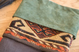Detail showing the rich texture of the green suede cuff and the woven antique rug fragment.