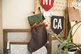 Green suede and antique rug fragment holiday stocking hanging, showing its black tassel.