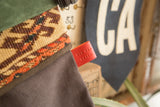 Embossed red leather Old New House tag on a stocking of linen and woven antique rug.