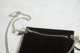 Silver metal zipper, grey suede pull, and chain strap on the black rug handbag.