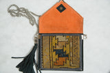 Open antique Caucasian rug fragment bag, orange suede interior, geometric yellow and orange pattern.
